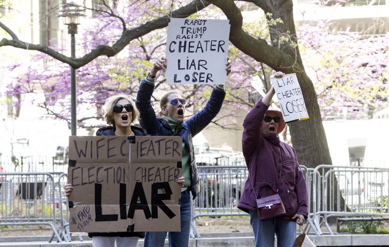 新聞媒體各有立場，對川普封口費案的報導方式有嚴重分歧；圖為三名女性在曼哈頓刑事法院外舉牌，稱川普「說謊者」。歐新社